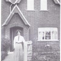 Mrs Puddephatt stands before No 9, New Cottages. The Bedford coronet marks the date of the building, 1867. From the collection of Rose Maling. Used with kind permission from Carolyn Birch.